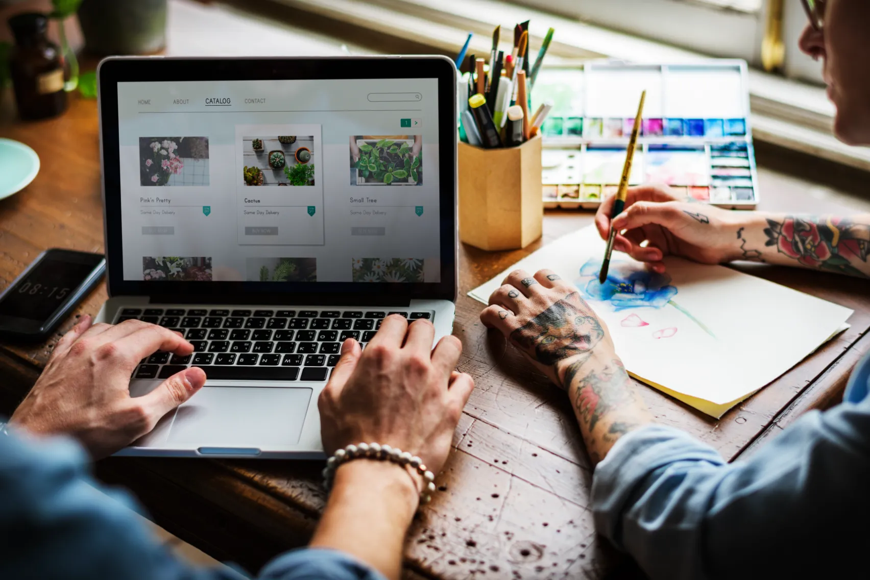 two people sitting at a computer collaborating on web design